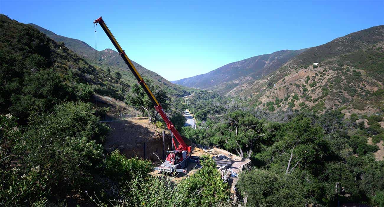 A crane lifting materials onto the rebuild site in the green canyon