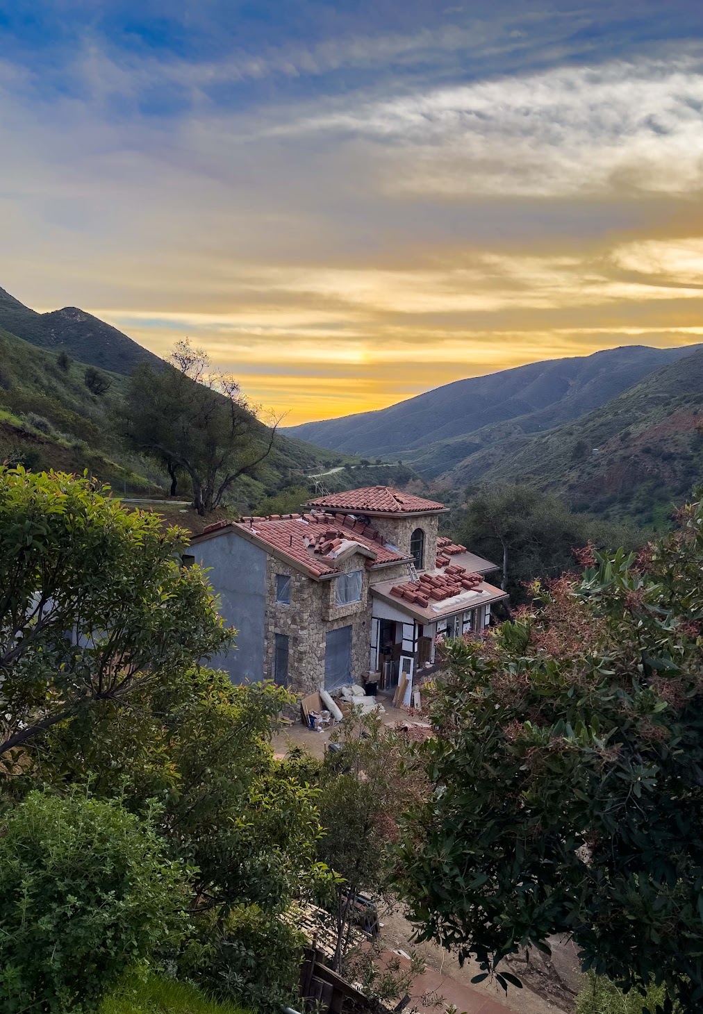 Evening light on the house, with the tower tiled and tile bundles still on the lower roofs.