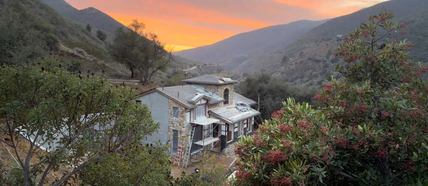 Stone guest house at sunset with mountains behind, newly rebuilt