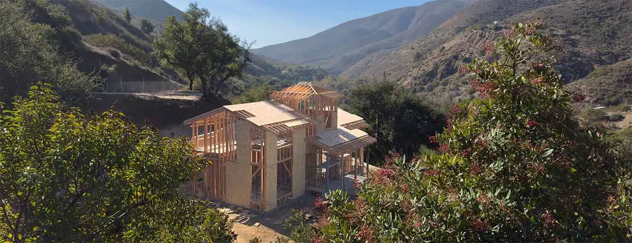 Timber framing of the new house against the mountains
