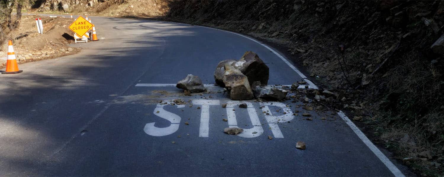 Rocks fallen onto a canyon road at a STOP marking