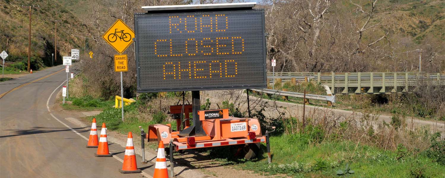 ROAD CLOSED AHEAD message sign and traffic cones on the canyon road