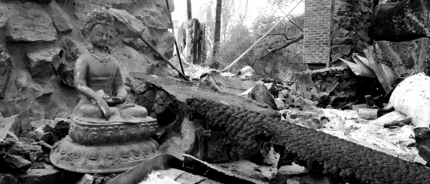 Buddha statue among burned debris, in black and white