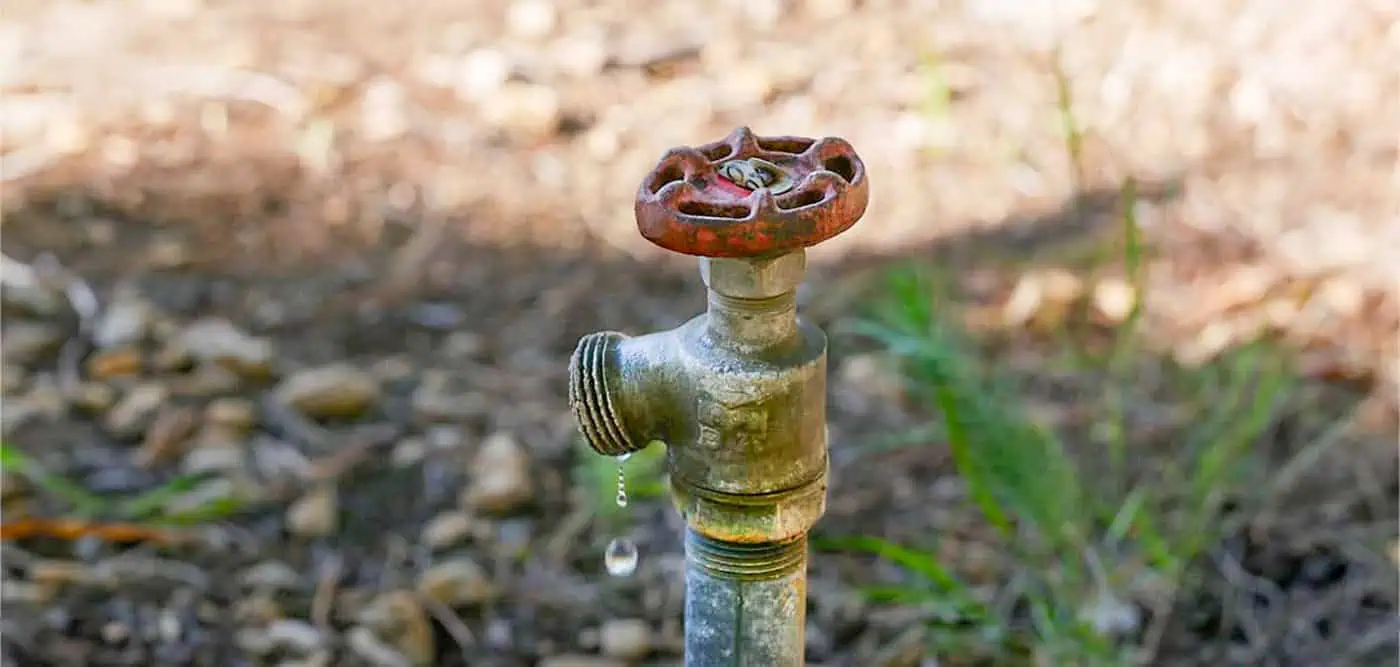 Water spigot dripping onto gravel