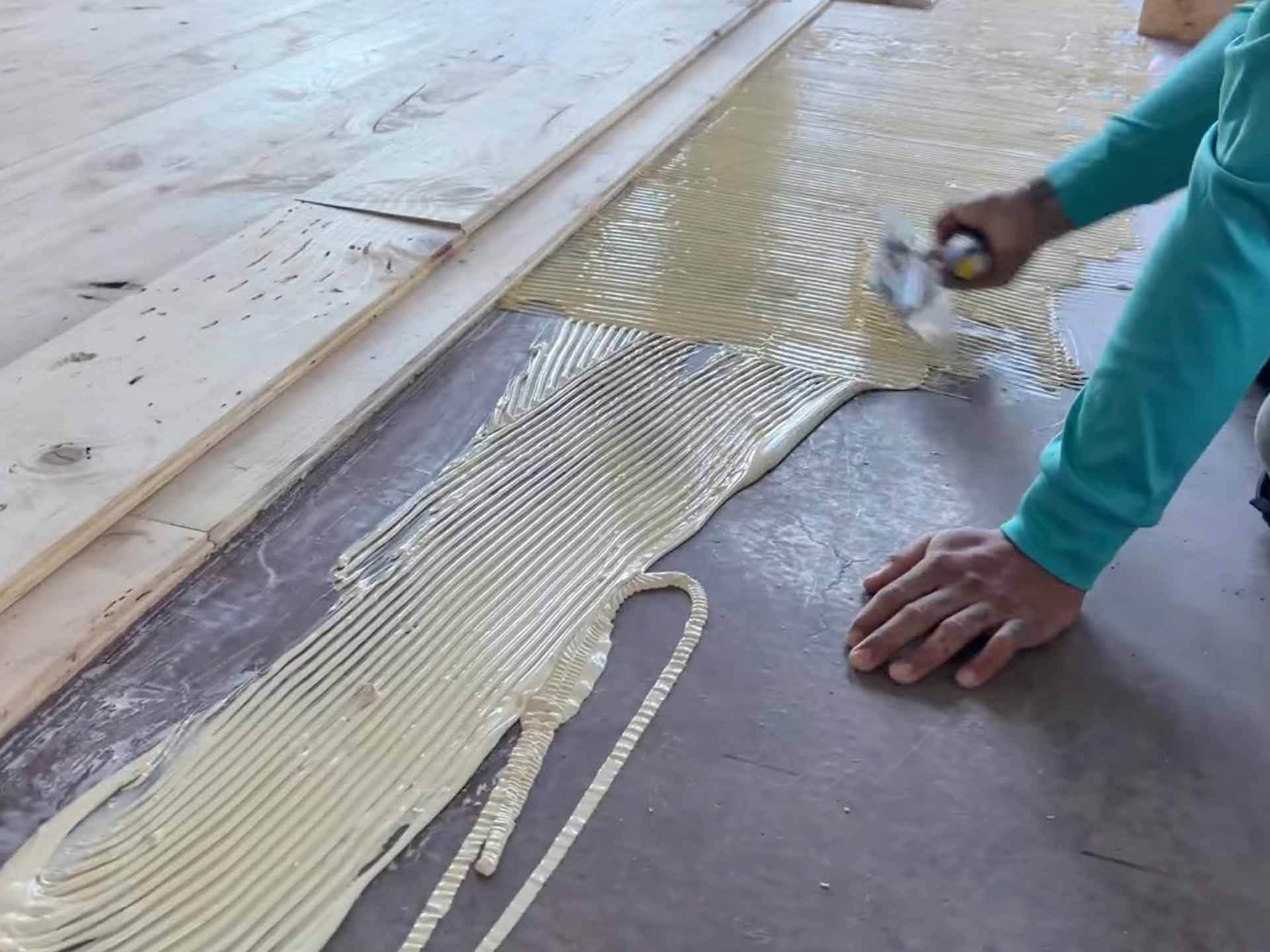 The boards are glued down to the subfloor with adhesive, laid in rows.